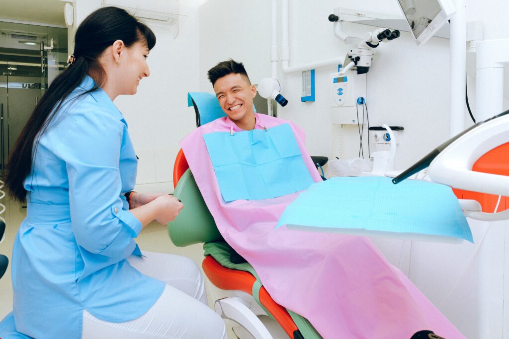 Cheerful ethnic male patient sitting in dental chair in clinic